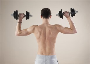Young man doing weight training with dumbbells