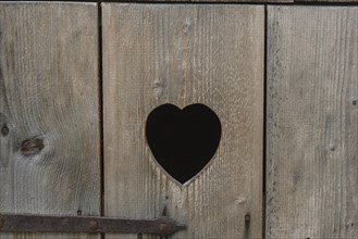 Heart-shaped cut-out in the wooden door of a toilet