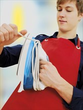Young man wearing an apron while doing the housework