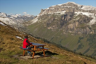 Walker looking from a rest area high above the Urnerboden high valley on the Klausen Pass