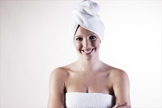 Portrait of a smiling young woman with a towel wrapped around her head