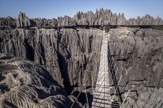 Tourist on suspension bridge over gorge in rugged limestone rocks