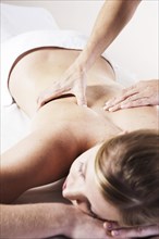 Young woman being massaged on the back by a therapist
