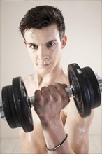 Young man doing weight training with dumbbells