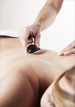 Young woman receiving a back massage with hot stones