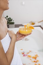 Woman drinking a cocktail in the bathtub