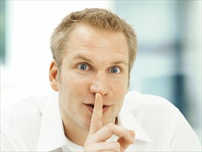 Businessman holding a finger in front of his mouth