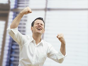 Businessman in an office cheering with clenched fists