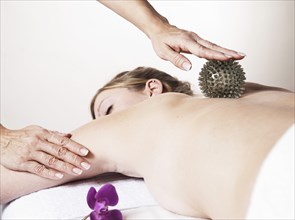 Young woman being massaged on the back with a spikey rubber massage ball