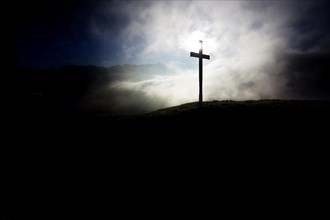 Summit cross of Gerenberg Mountain with high fog in front of the Alpstein Mountains