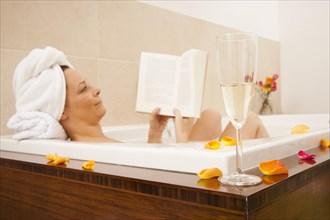 Woman taking a bath and reading a book