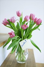 Tulips in a vase with the note 'danke'