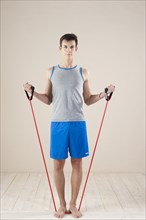 Young man doing strengthening and stretching exercises with a rubber rope