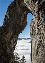 View through natural arch Breitensteinfensterl to high fog above the valley