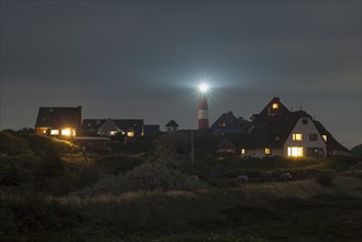 Lighthouse and thatched houses at night