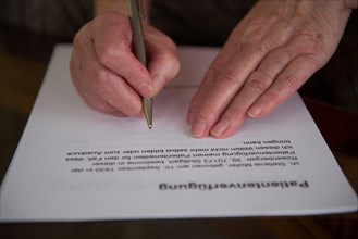 Hands of a 82-year-old woman signing a living will