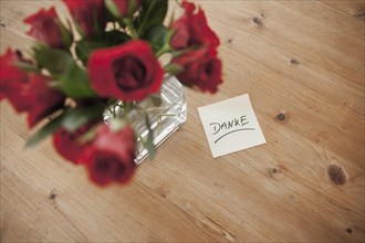 Red roses in vase with the note 'danke'