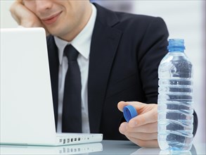 Businessman in an office with a laptop and a water bottle