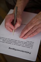 Hands of a 82-year-old woman signing a living will