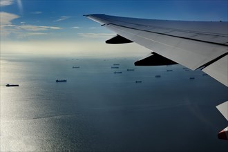 Wing of a plane with views of the port area of Jakarta on landing approach