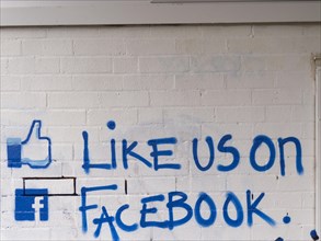 Like us on facebook' call to action painted on a brick wall