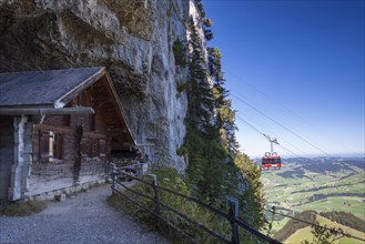 Wooden hut at the Wildkirchli Cave with a gondola of the Ebenalp cable car