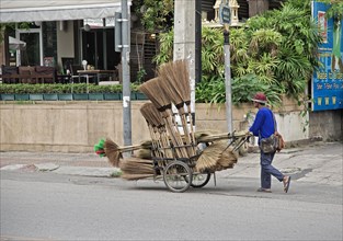 Broom merchant pushing his wares through the streets