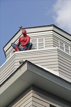 Spiderman sitting on a house
