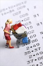 Miniature figurine of a woman with a shopping chart on a receipt