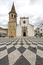 Church and bell tower of Sao Joao Baptista with a geometric paving pattern on the marketplace of Tomar