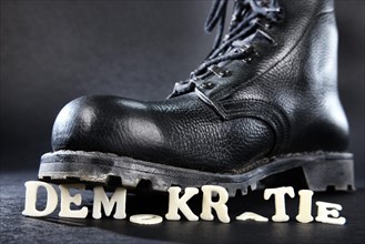 Combat boot standing on the word 'Demokratie'