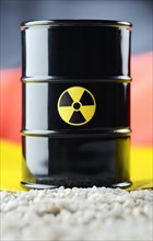 Barrel of nuclear waste in front of a German flag