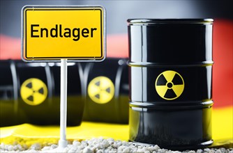 Three barrels of nuclear waste in front of a German flag and a town sign with the name 'Endlager'