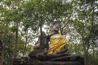 Seated Buddha statue in front of a chedi