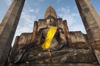 Seated Buddha statue in front of a chedi