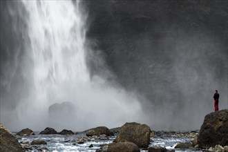 A tourist is standing at the Haifoss waterfall on the Fossa i Thjosardal river