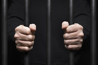 Hands of prisoner around prison bars