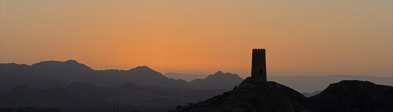 Sunrise over Al-Mudayrib with the silhouette of a lone watch tower