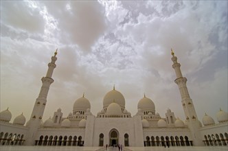 Dark clouds above the courtyard and its archway of the Sheikh Zayed Grand Mosque