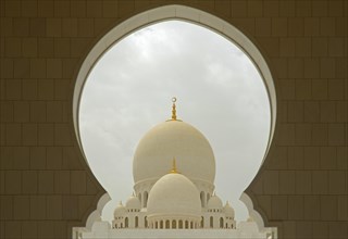 White domes seen through the top of an arch of the archway of Sheikh Zayed Grand Mosque