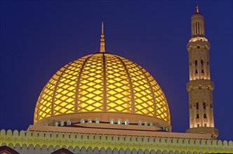 The flood-lit dome and minaret of Sultan Qaboos Grand Mosque at the blue hour