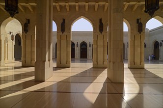 The columns and arches of an archway inside Sultan Qaboos Grand Mosque