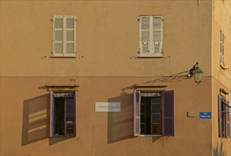 A facade in Ajaccio with open and closed windows illuminated by warm morning light. Ajaccio is the capital of the mediterranean island of Corsica