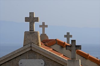 Crucifixes of the typical above-ground tombs in the cemetery of Ajaccio with the water of the mediterranean sea in the background. Ajaccio is the capital of the mediterranean island of Corsica