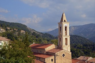 The church of the small village Evisa illuminated by warm evening light surrounded by mountains. Evisa is in the department Corse-du-Sud