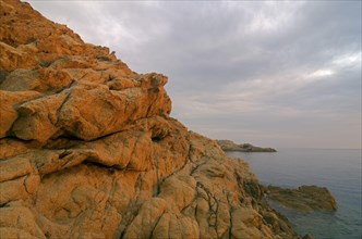 The red granite rocks of the island Ile de la Pietra near L'Ile-Rousse illuminated by the first light of the day. L'Ile-Rousse is in the department Haute-Corse
