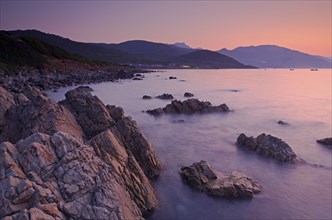 Sunrise behind the mountains of Corsica near Ajaccio with the rocky mediterranean coast on the foreground. Ajaccio is the capital of the mediterranean island of Corsica