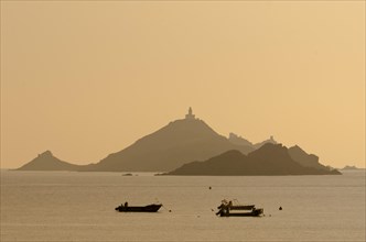 The silhouette of the islands Les Iles Sanguinaires with small boats in the foreground. Les Iles Sanguinaires are in the department Corse-du-Sud