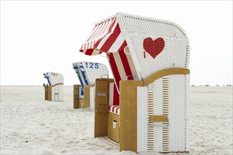 Roofed wicker beach chair with a red heart on the beach