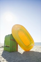 Colourful roofed wicker beach chair and a yellow inflatable boat